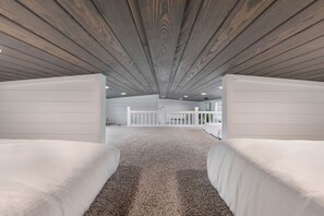 Ein Zimmer mit zwei Betten, einem weißen Geländer und einer schrägen Decke.