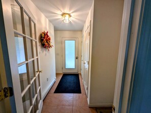 A hallway with a door, a mat, and a wreath on the wall. - Serene Lakeside Cabin with Fire Pit, Waterfront Retreat Near Graham Lake, Mariaville Maine (Mariaville)