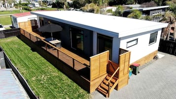 A modern, single-story building with a flat roof, large windows, and a wooden deck.