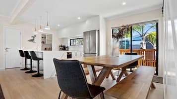 A modern kitchen with a central island, bar stools, and a dining table with benches.