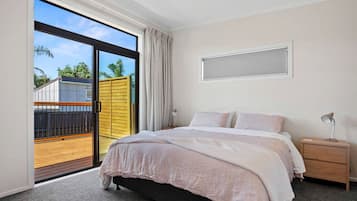 Quarto com cama, mesa de cabeceira, luminária, janela e vista para uma varanda.