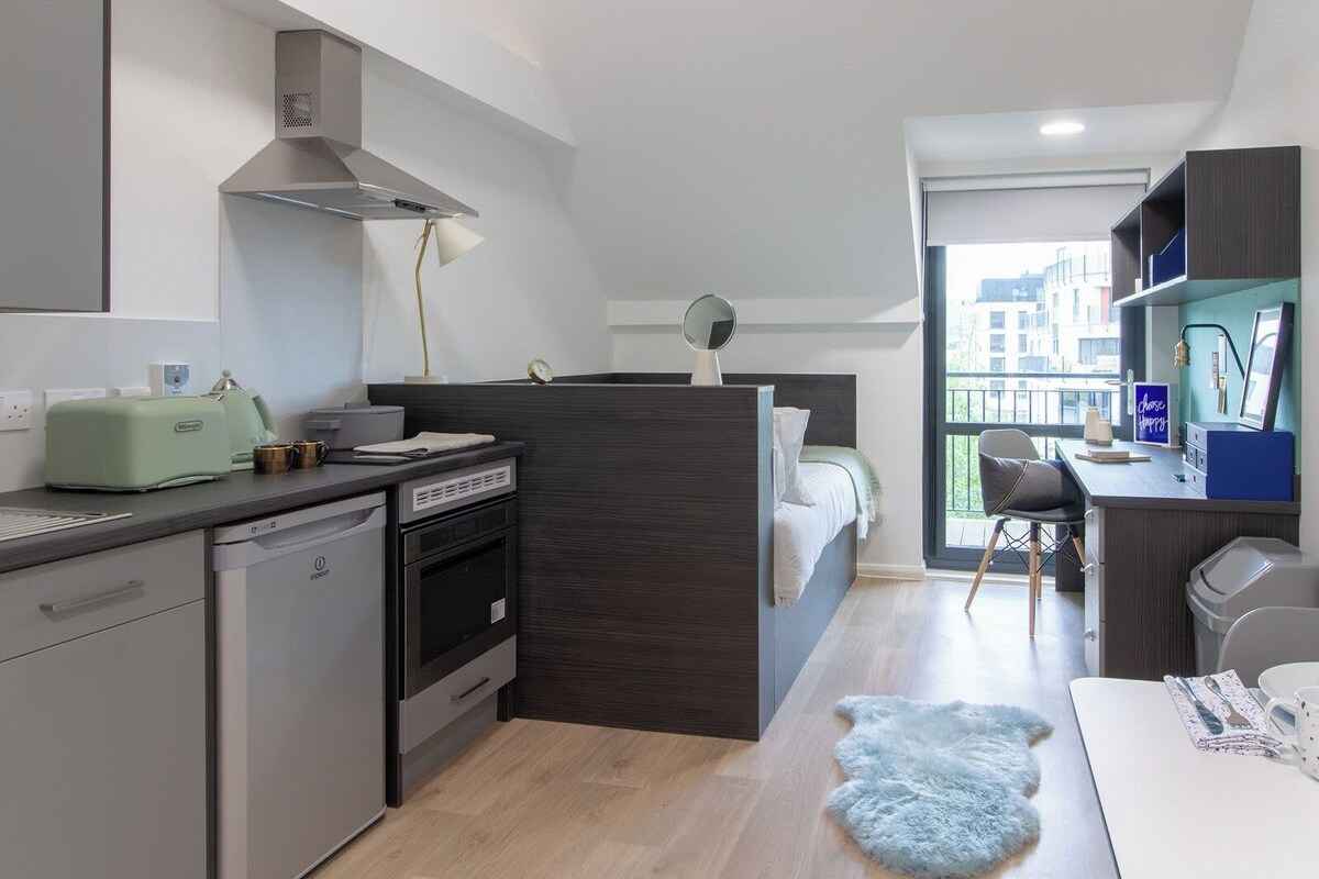 A compact kitchenette with a modern stove, a small refrigerator, and a microwave.
