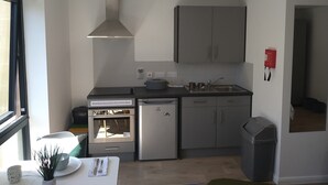 A modern kitchen with a built-in oven, refrigerator, and a large grey cabinet. - Avon Studios Bath (Bath)