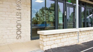 A building with a sign reading 'AVON STUDIOS' on the facade, large glass windows, and a stone wall in front. - Avon Studios Bath (Bath)
