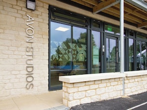 A building with a sign reading 'AVON STUDIOS' on the facade, large glass windows, and a stone wall in front. - Avon Studios Bath (Bath)