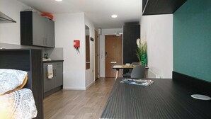 A modern kitchen with grey cabinets, a wooden dining table, and a green accent wall. - Avon Studios Bath (Bath)