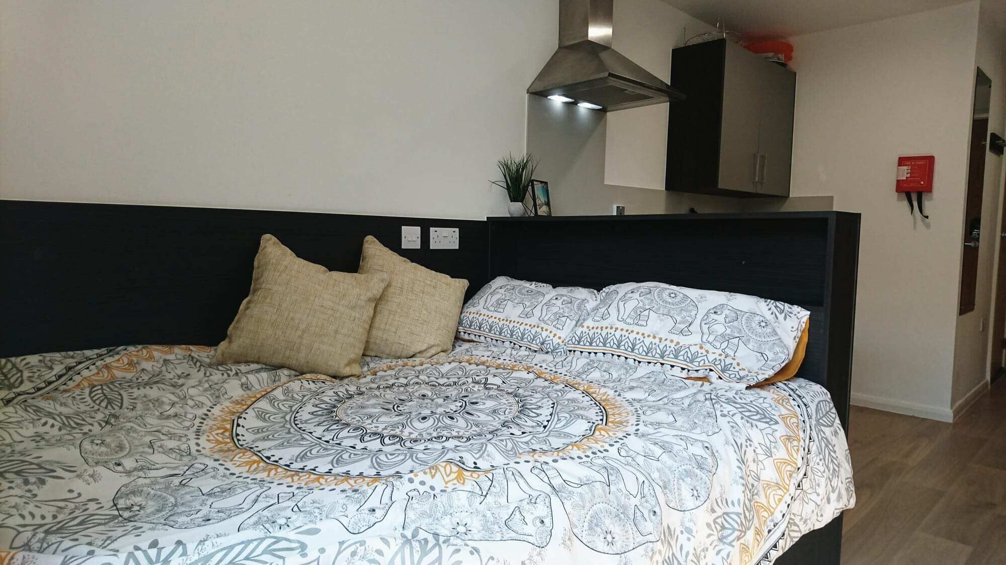 Una cama con ropa de cama estampada, cabecera oscura y dos almohadas.