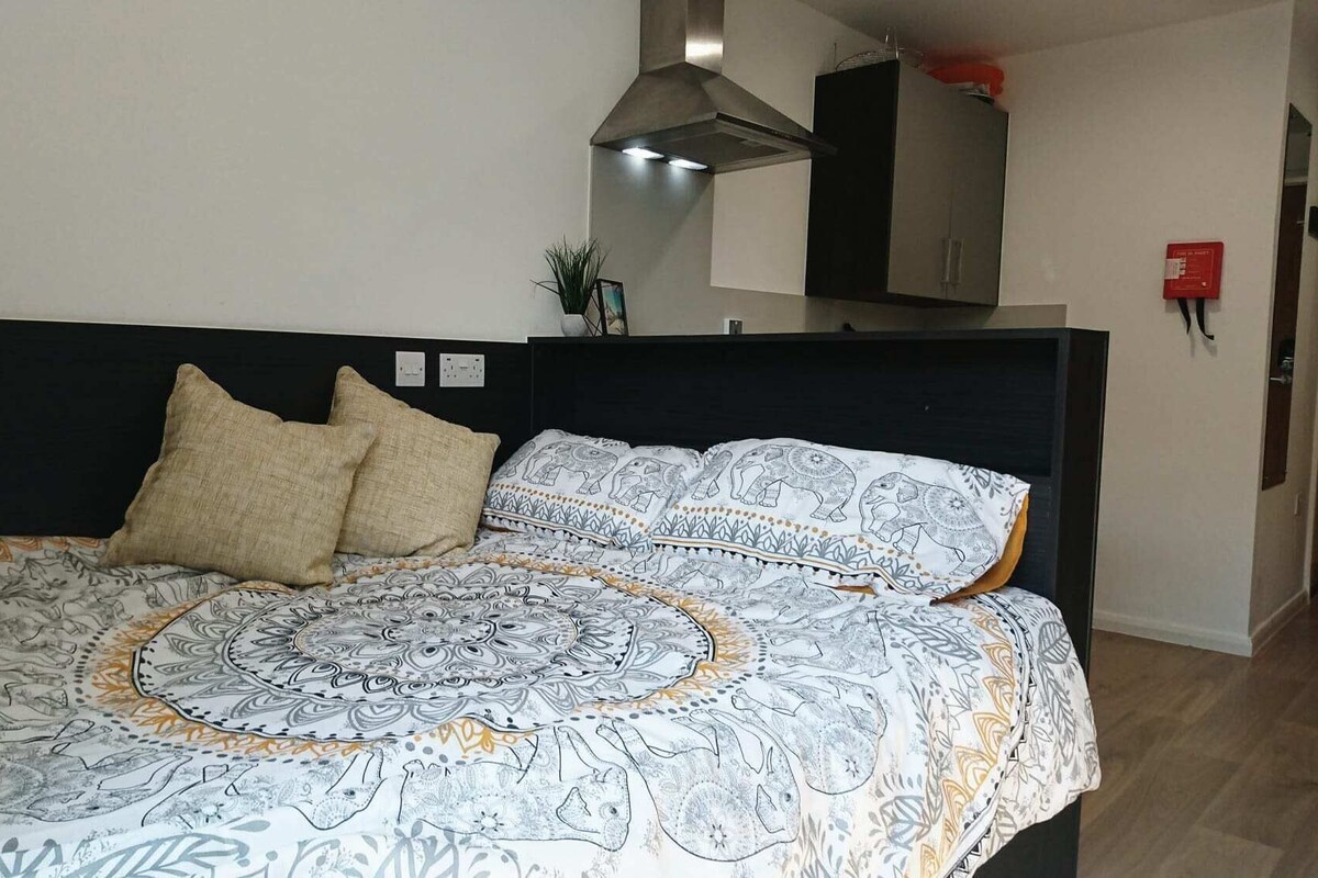 A bed with patterned bedding, a dark headboard, and two pillows.