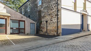 Un bâtiment en pierre avec une entrée au rez-de-chaussée, un petit porche et une rue pavée.