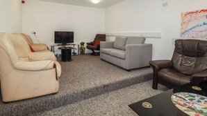 Un salon comprenant un canapé, des fauteuils, un téléviseur et une table basse.