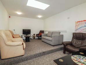 A living room with a sofa, armchairs, a television, and a coffee table. - Newseal House (St Austell)