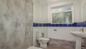 Une salle de bain comprenant une douche à parois de verre, des toilettes, une baignoire et un lavabo.