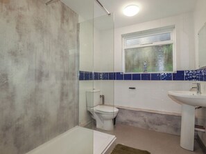 A bathroom with a glass shower enclosure, a toilet, a bathtub, and a sink. - Newseal House (St Austell)