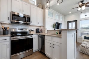 A modern kitchen with stainless steel appliances, white cabinetry, and a wooden countertop. - Contemporary Tiny Home Escape with Resort Amenities Near Fredericksburg, TX (Fredericksburg)