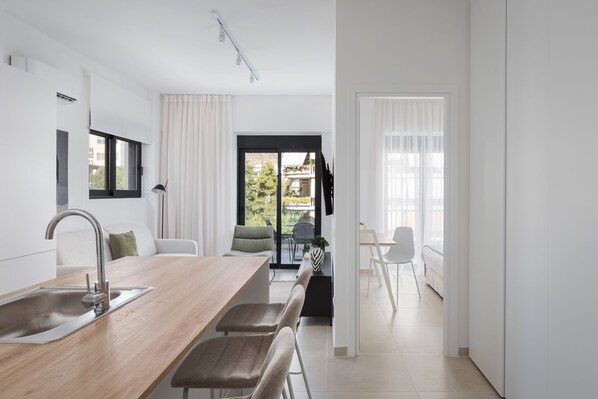 Una cocina moderna con encimera de madera, pileta de acero inoxidable y una zona de comedor con banco y sillas.