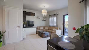 Ein modernes Wohnzimmer mit Sofa, Couchtisch, Fernseher und Essbereich mit Tisch und Stühlen.