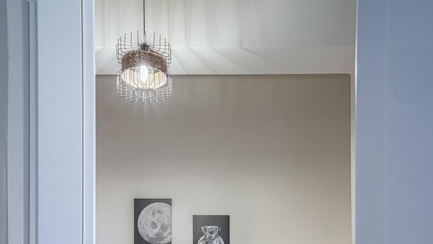 Ein Schlafzimmer mit einem Bett, zwei Kissen, einem Nachttisch mit Lampe und zwei gerahmten Bildern an der Wand.