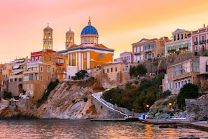 A coastal town with a prominent church featuring a blue dome and two bell towers, surrounded by colorful buildings. - Syros Sun Airport Villa Open Views Near Ermoupoli (Syros)