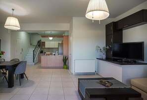 A modern living room with a TV, sofa, and dining area. - Syros Sun Airport Villa Open Views Near Ermoupoli (Syros)