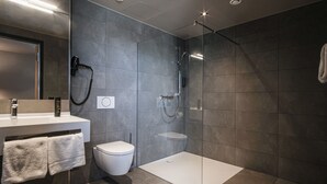 Une salle de bain moderne avec une douche à parois de verre, des toilettes blanches et un meuble-lavabo agrémenté d’une serviette.