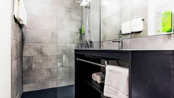 A modern bathroom with a glass-enclosed shower, a black vanity, and a towel rack.