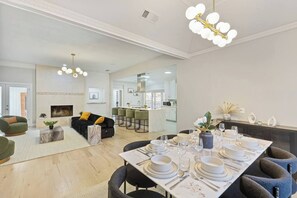 Una sala de estar moderna con un sofá, una mesa de comedor para cuatro personas y una cocina al fondo.
