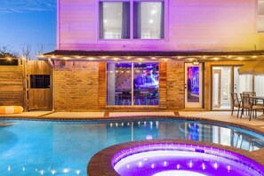Una piscina con jacuzzi, un patio techado y un bar con vista a una cascada.