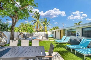 A backyard with a table, chairs, a hammock, and a pool area. - Stylish Surf-Themed Beach House with Private Pool Near Pompano Beach Pier, Pompano Beach Florida (Pompano Beach)