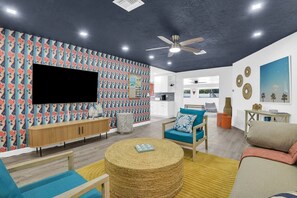 A modern living room with a flat-screen TV, a round woven coffee table, and a sofa. - Stylish Surf-Themed Beach House with Private Pool Near Pompano Beach Pier, Pompano Beach Florida (Pompano Beach)