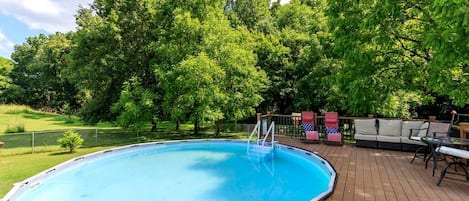 Piscina con cubierta de madera, rodeada de árboles.