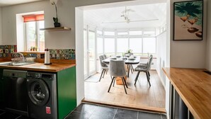 Eine moderne Küche mit Waschmaschine, eine Essecke mit Tisch und Stühlen sowie ein großes Fenster für natürliches Licht.