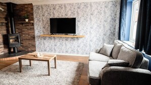 Ein Wohnzimmer mit Kamin, Flachbildfernseher, einer Couch und einem Couchtisch.