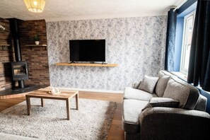 Una sala de estar con chimenea, televisor de pantalla plana, sofá y una mesa de centro.