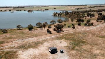 An aerial view of a rural landscape with a lake, trees, and a fenced area with a small building.
