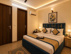 A hotel room with a large bed, a bedside table with a lamp, a wall-mounted air conditioner, and a framed artwork above the bed. - Hotel Kasa Stays -  Ramesh Nagar Metro  (New Delhi)