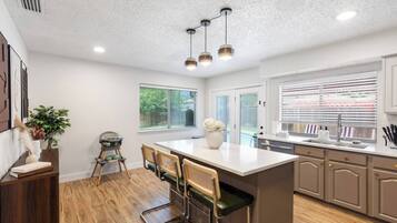 Une cuisine moderne dotée d’un îlot central, de planchers en bois et de luminaires suspendus.