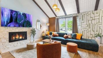 Un salon moderne avec une cheminée, un grand téléviseur à écran plat, un canapé avec des coussins et une table basse.
