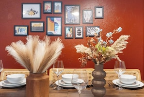 A dining table set with plates, glasses, and a vase with dried flowers.