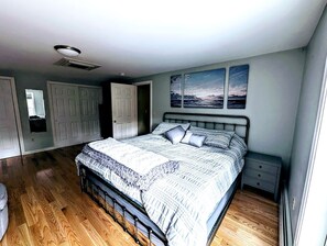 Ein Schlafzimmer mit einem Bett, einem Nachttisch, einer Kommode und einer Tür.