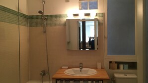 Een badkamer met een douche, een wastafel, een spiegel en een toilet.