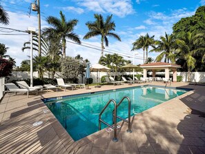 A swimming pool with lounge chairs and palm trees. - Modern Gated Townhouse with Heated Pool Access Near Beaches – Pompano Beach, Florida (Pompano Beach)