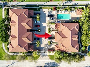 Vue aérienne d’une propriété dotée d’une piscine, de plusieurs places de stationnement et d’une route principale.