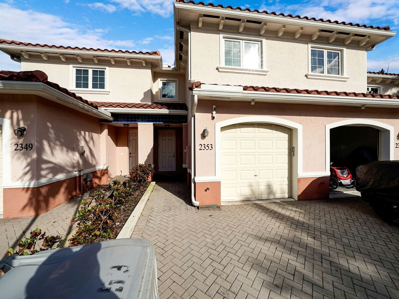 A two-story residential building with a garage and a driveway.