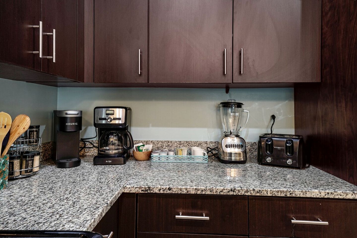 A kitchen with dark wooden cabinets, a coffee maker, a blender, and a toaster.