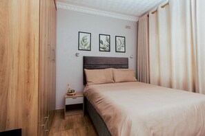 Ein Schlafzimmer mit einem Bett, einem Nachttisch und drei gerahmten Pflanzenbildern an der Wand.
