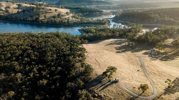 An aerial view of a landscape with a river, dense forest, and a winding road.