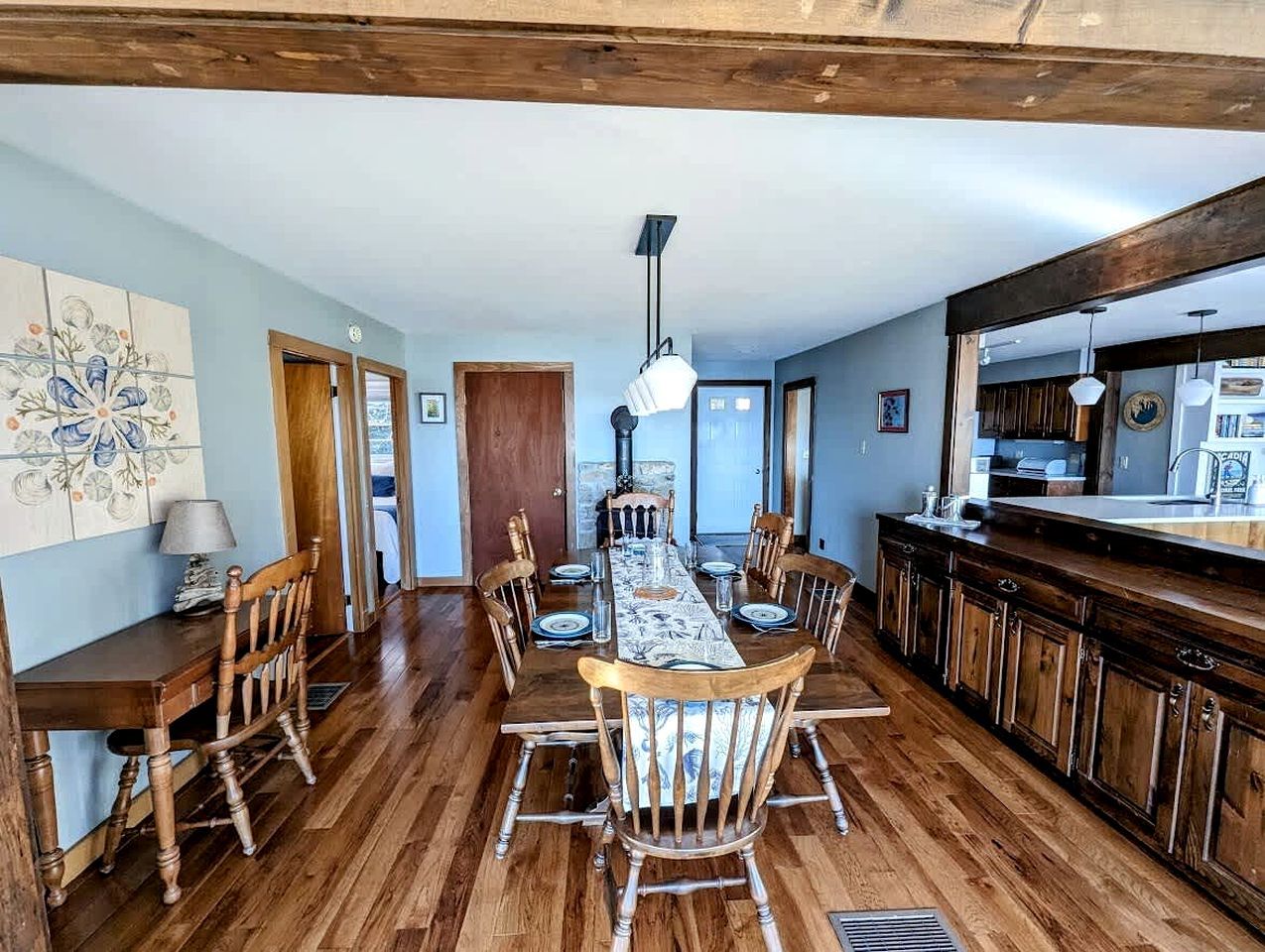 Un comedor con una mesa y sillas de madera, una cocina con armarios de madera oscura y un ventanal grande.