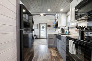 Eine moderne Küche mit einem schwarzen Kühlschrank, Edelstahlgeräten und Holzboden.