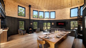 A spacious room with a high ceiling, large windows, a fireplace, and a Netflix screen.