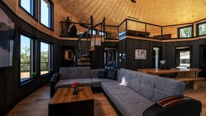 A spacious living area with a large gray sectional sofa, a wooden coffee table, and a staircase leading to an upper level.